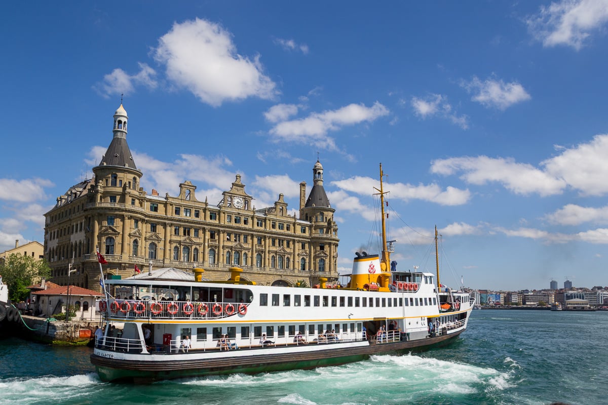 Communting Istanbul by ferry passing by Haydarpasa Terminal under a bright blue sky.
