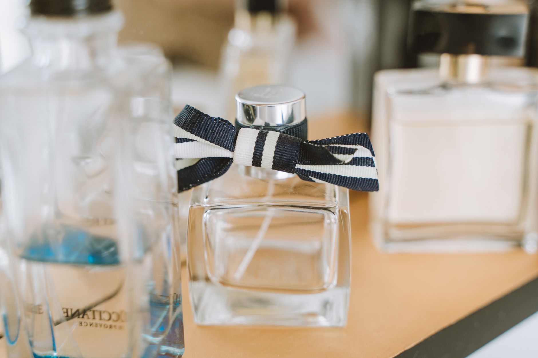 Flakonikiem perfum z czarno-białą wstążką na drewnianym stole między innymi buteleczkami