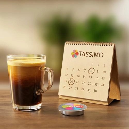TASSIMO calendar with date marked and cup of black coffee with colorful pod beside it